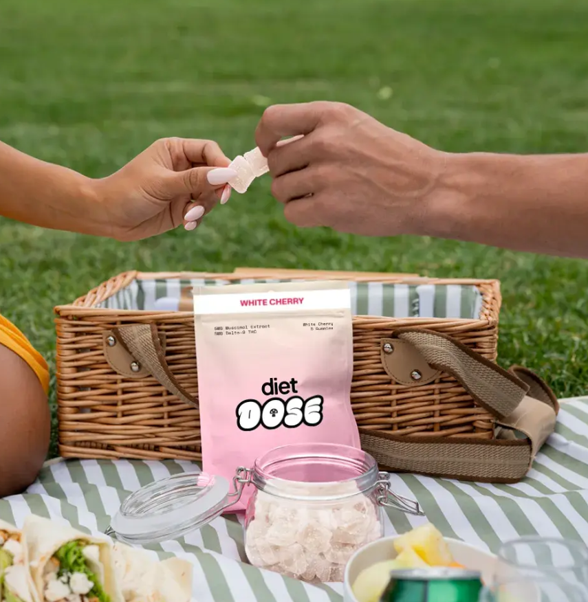 A person taking a gummy from a package during a picnic.