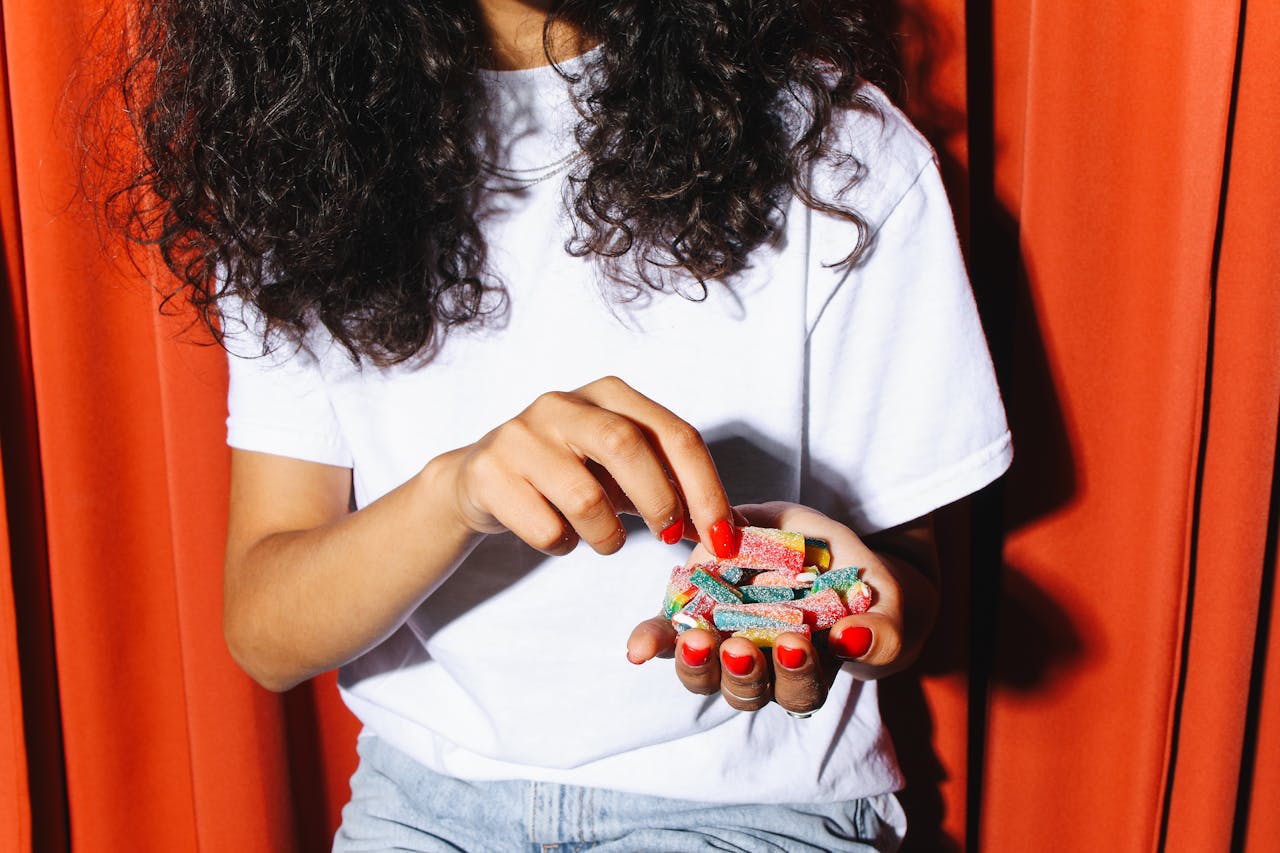 Person holding a variety of colorful THC gummies in a bowl