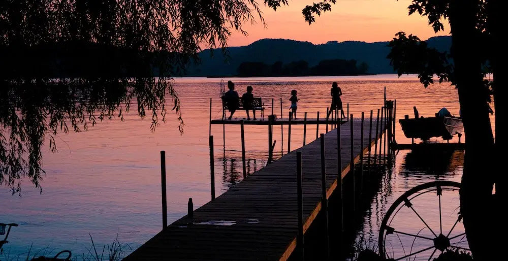 Silhouette of people on a dock at sunset over a lake.