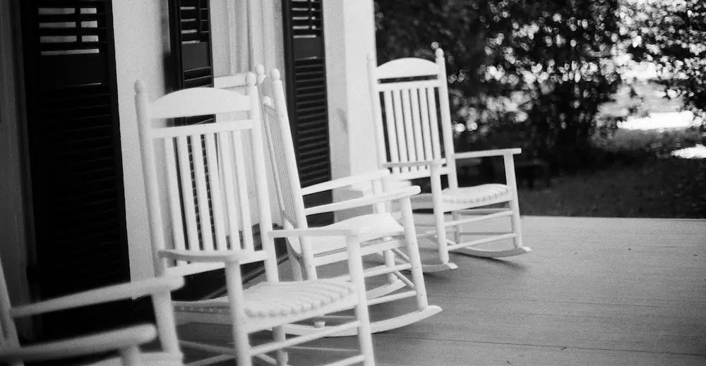 A row of white rocking chairs on a porch