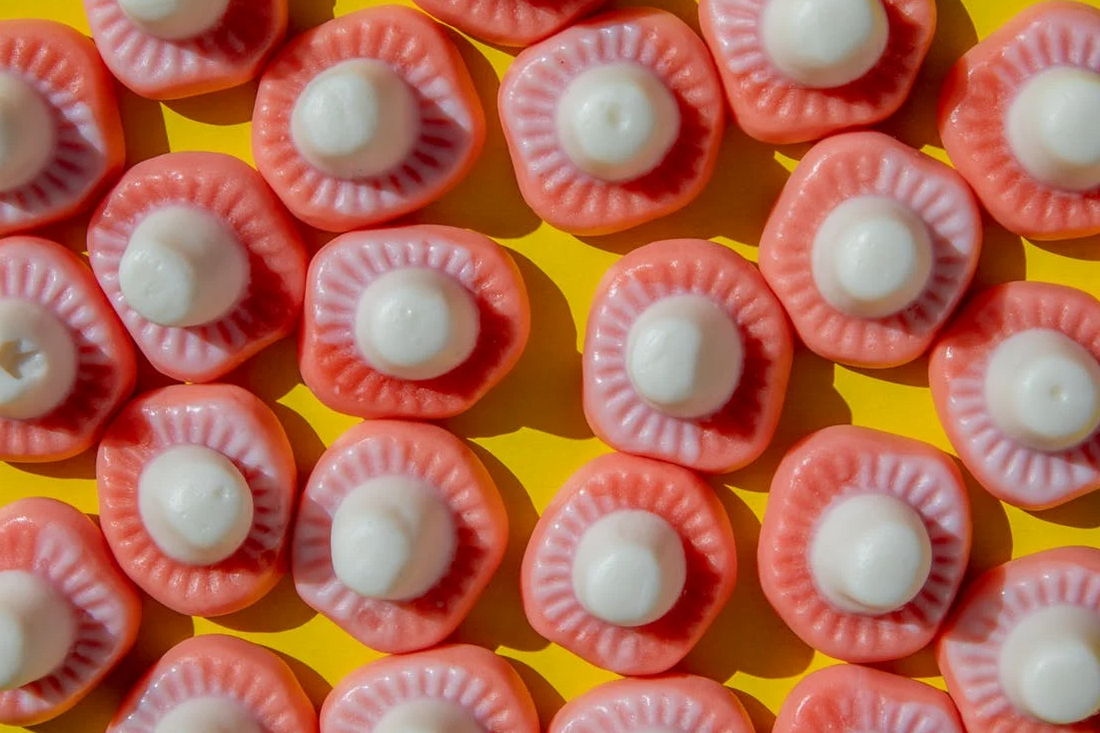 Colorful gummy candies resembling mushroom shapes on a yellow background.