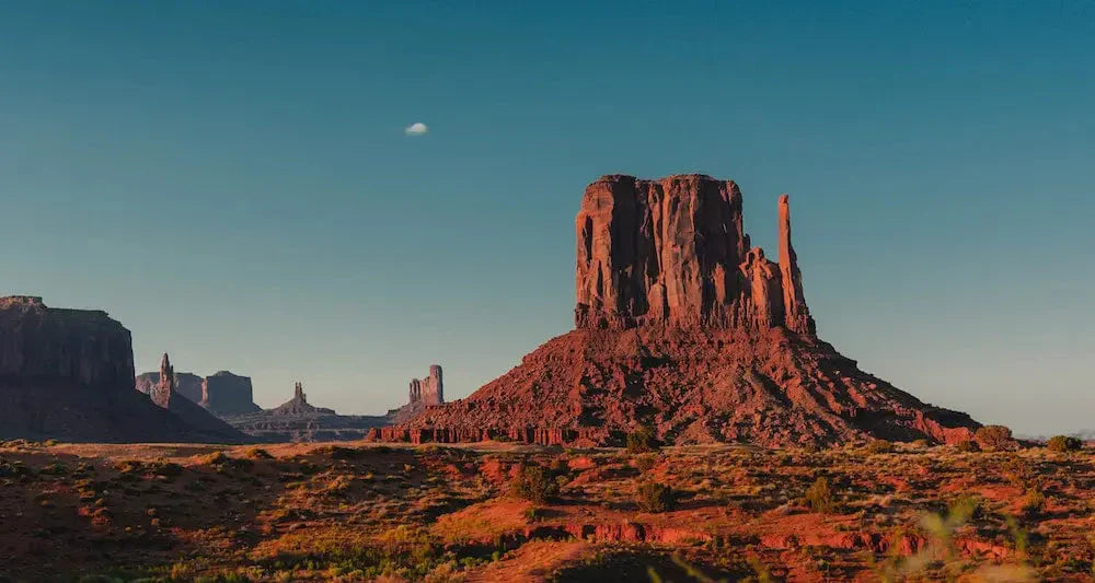 A scenic view of Monument Valley with red rock formations under a clear blue sky.