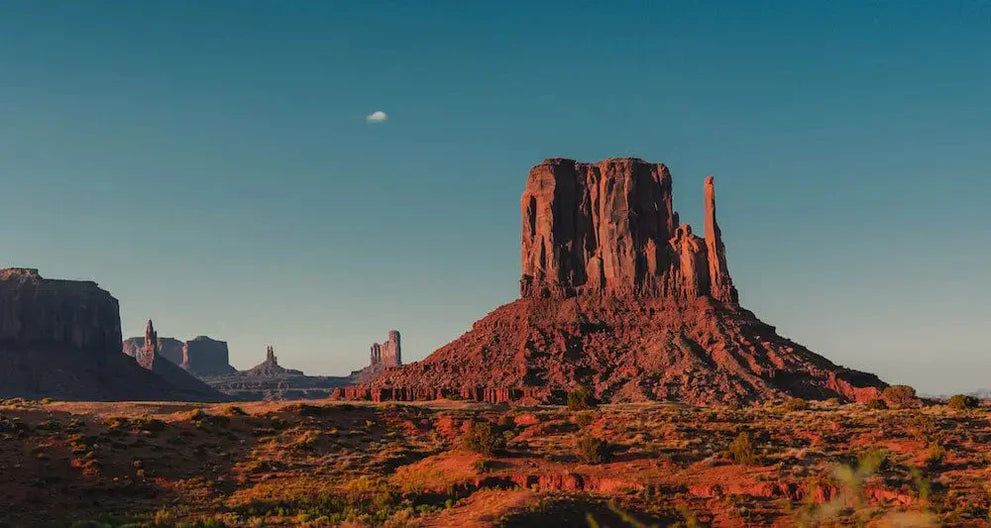 A scenic view of Monument Valley with red rock formations under a clear blue sky.