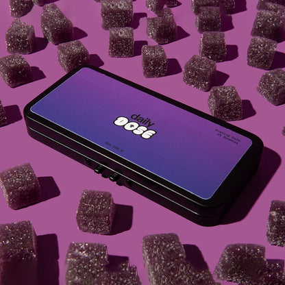 A box labeled 'daily dose' surrounded by purple gummies on a pink background.