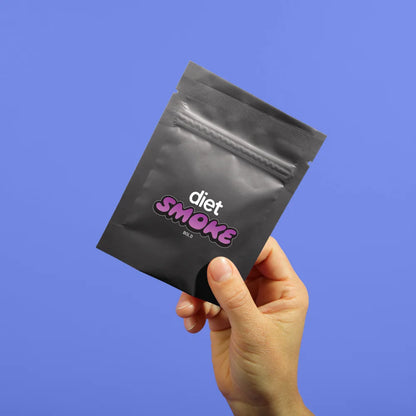A hand holding a black package labeled 'diet SMOKE' against a blue background.