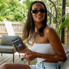 A woman holding a package of Blue Boomers gummies, smiling outdoors.