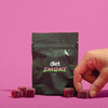 A hand reaching for Cherry Lime gummies from a black package labeled 'diet SMOKE' on a pink background.