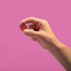 A hand holding a Cherry Lime gummy against a pink background