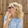 Woman enjoying Morning Punch gummies outdoors, wearing sunglasses.