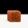 A single orange Amanita gummy candy on a white surface