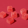 Six red gummy candies on a red background.