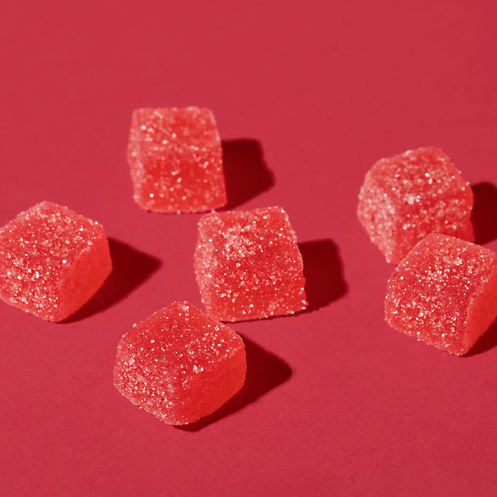 Six red gummy candies on a red background.